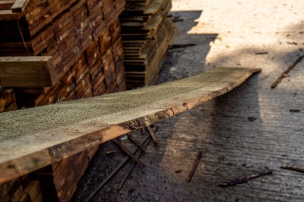 A Douglas Fir waney edge cladding board across the stacks with sawdust texture at Valley Sawmills